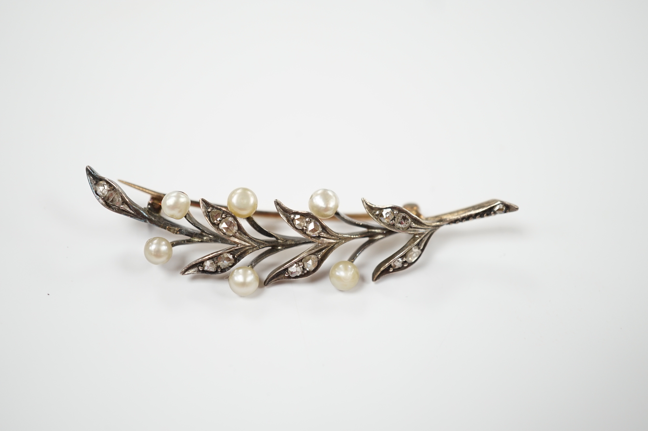 An early 20th century yellow metal, cultured pearl and rose cut diamond set foliate spray brooch, 58mm, gross weight 5.8 grams.